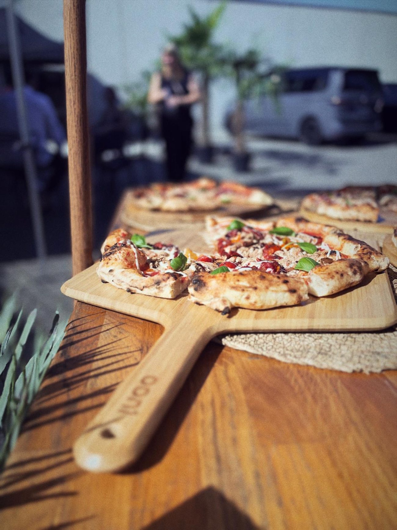Mehrere Pizzen auf Holzschiebern, aufgereiht auf der Theke während eines Events