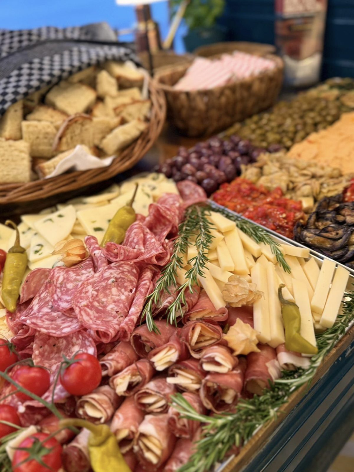 Wurst- und Käseplatte mit Schinkenröllchen, Salami und Käse, dahinter der Brotkorb